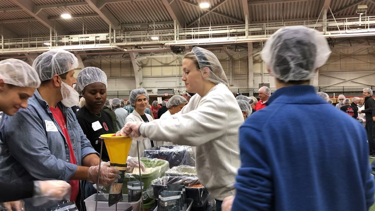 Students, staff and alumni prepare meals for vets in an assembly line set-up