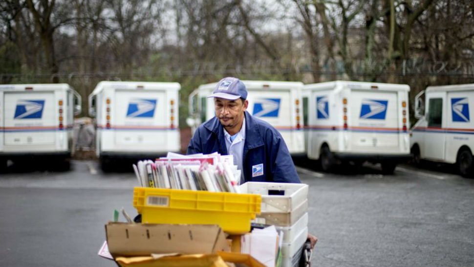 In this Feb. 7, 2013 file photo, a U.S. Postal Service letter carrier gathers mail to load into his truck before making his delivery run in the East Atlanta neighborhood in Atlanta. As consumers demand ever-quicker and convenient package delivery, the U.S. Postal Service wants to boost its business this holiday season by offering what few e-commerce retailers can provide: cheap next-day service with packages delivered Sundays to your home. (AP Photo/David Goldman, File)