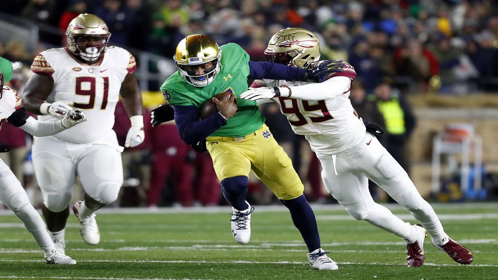 Notre Dame quarterback Brandon Wimbush, center, tries to break the tackle of Florida State defensive end Brian Burns, right.  Wimbush started in place of injured QB Ian Book and led the Fighting Irish to a 42-13 win over Florida State.  (AP Photo/Paul Sancya)
