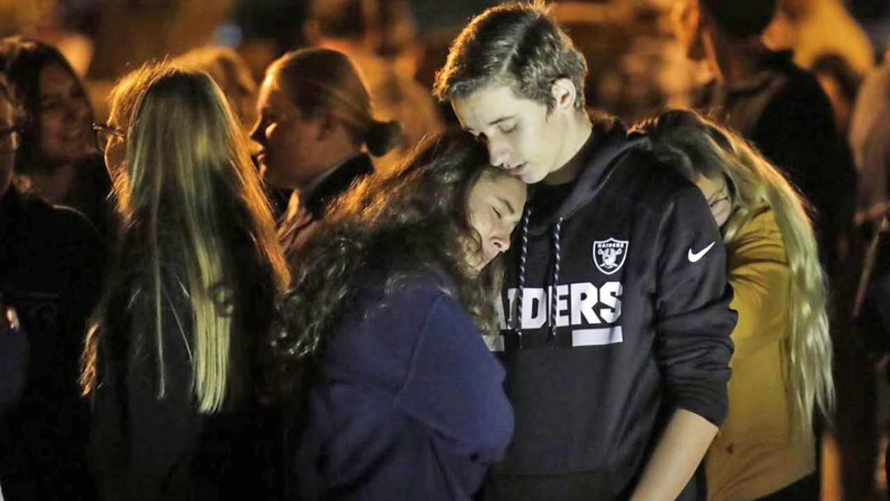 Hannah Schooping-Gutierrez, center, a student at Saugus High School, is comforted by her boyfriend Declan Sheridan, at right, a student at nearby Valencia High School during a vigil at Central Park in the aftermath of a shooting at Saugus Thursday, Nov. 14, 2019, in Santa Clarita, Calif. (AP Photo/Marcio Jose Sanchez)