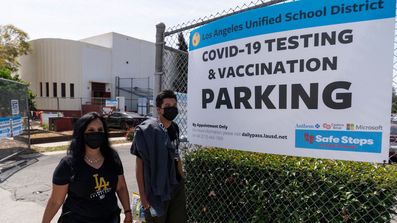 In this April 15, 2021, file photo, parent Rosa Vargas and her son, 9th grade student Victor Loredo, 14, walk home after getting tested at a Los Angeles Unified School District COVID-19 testing and vaccination site in East Los Angeles.(AP Photo/Damian Dovarganes, File)