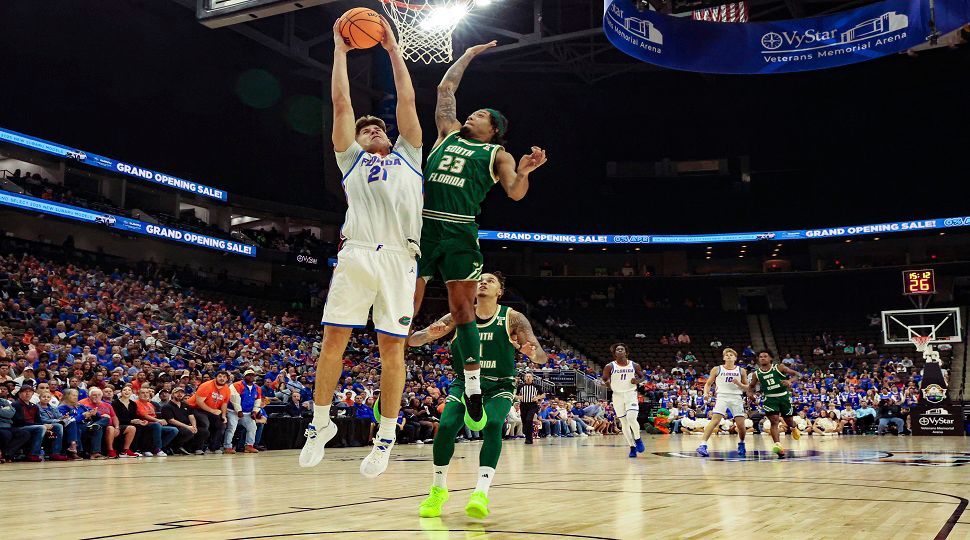 Florida forward Alex Condon (21), left, takes the ball to the basket defended by South Florida guard Quincy Ademokoya (23) during the first half of an NCAA college basketball game, Monday, Nov. 4, 2024, in Jacksonville, Fla. (AP Photo/Gary McCullough)