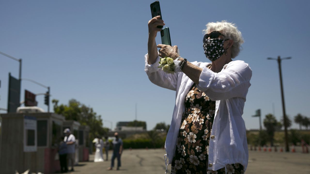 Patty Luce records video during her daughter's marriage service in the parking lot of the Honda Center in Anaheim, Calif., Tuesday, May 26, 2020.