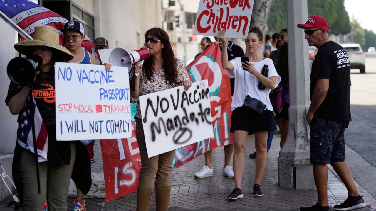Anti-vaccine mandate protesters rally outside the garage doors of the Los Angeles Unified School District, LAUSD headquarters in Los Angeles on Sept. 9, 2021. (AP Photo/Damian Dovarganes)