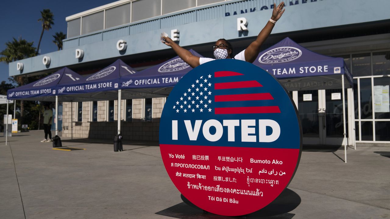 Ericia Leeb takes pictures with an "I Voted" sign after voting at Dodger Stadium in Los Angeles, Saturday, Oct. 31, 2020. (AP Photo/Jae C. Hong)