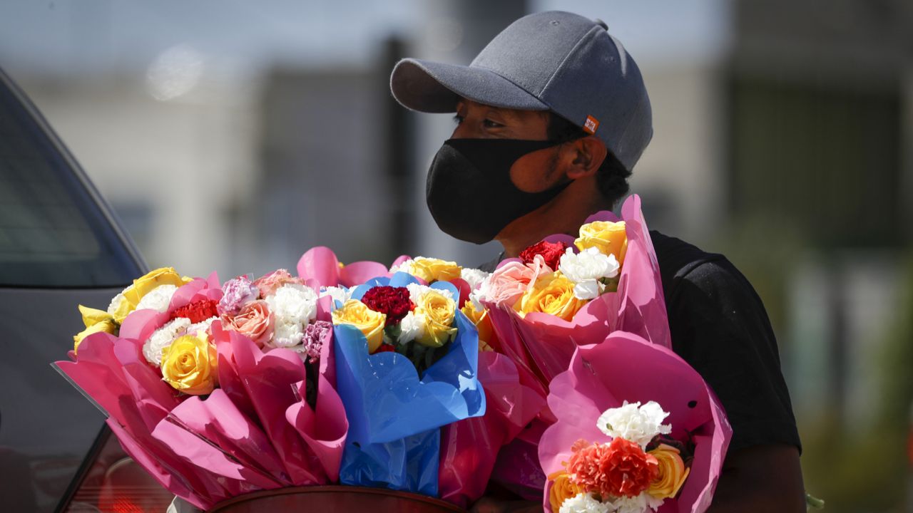 A street vendor wearing a face mask sells flowers Thursday, May 7, 2020, in Anaheim, Calif. (AP Photo/Chris Carlson)