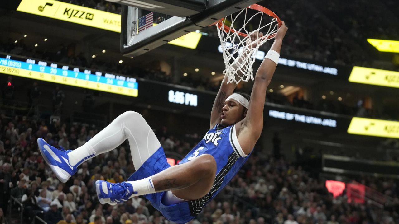 The Orlando Magic's Paulo Banchero hangs on to the rim after a first-half dunk during Thursday night's game against the Utah Jazz. (AP Photo/Rick Bowmer)