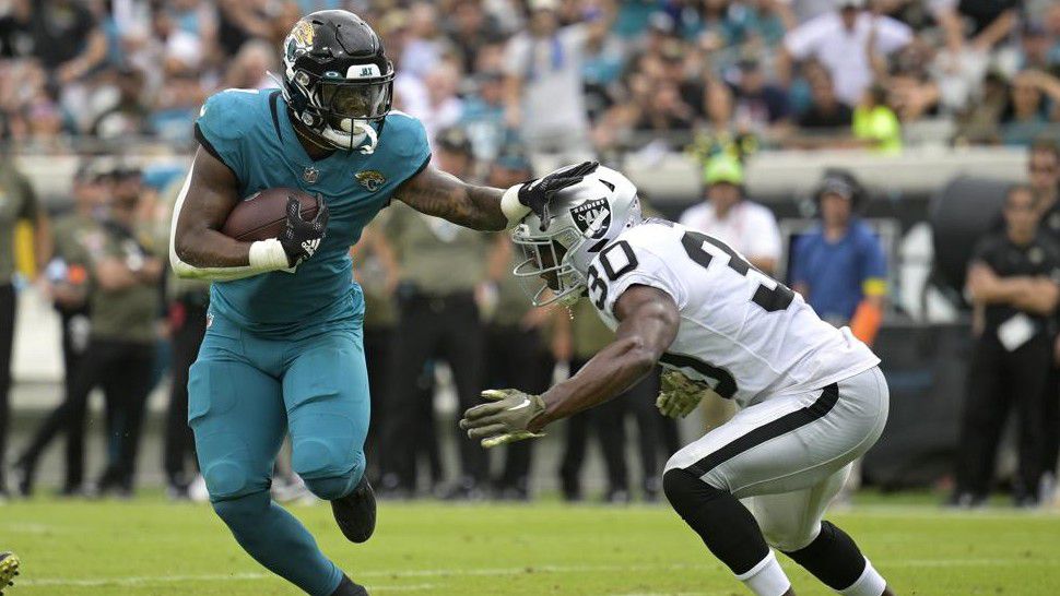 Jacksonville Jaguars running back Travis Etienne Jr. (1) tries to get past Las Vegas Raiders safety Duron Harmon (30) in the first half of an NFL football game Sunday, Nov. 6, 2022, in Jacksonville, Fla. (AP Photo/Phelan M. Ebenhack)