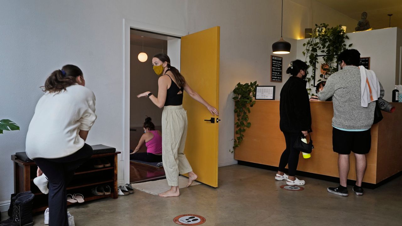 Yoga instructor Lydia Stone, center, welcomes patrons arriving for a morning yoga class at the Highland Park Yoga studio in Los Angeles, Saturday, Nov. 6, 2021. (AP Photo/Damian Dovarganes)