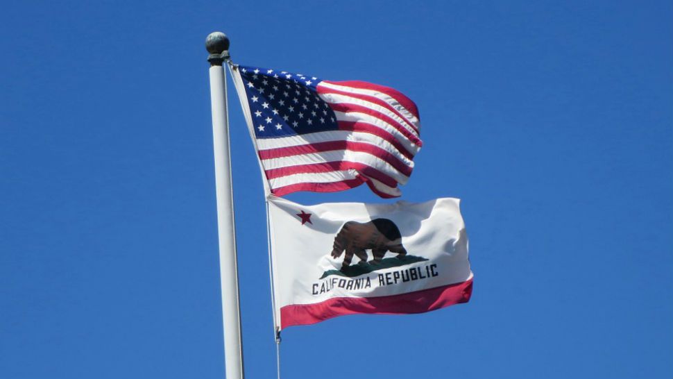A U.S. flag flies above a California state flag.