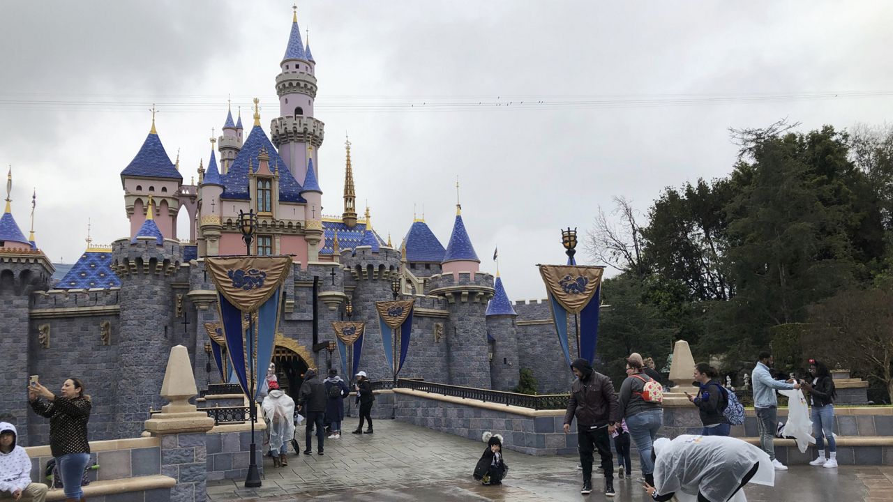 Visitors take photos at Disneyland in Anaheim, Calif. on March 13, 2020. (AP Photo/Amy Taxin, File)