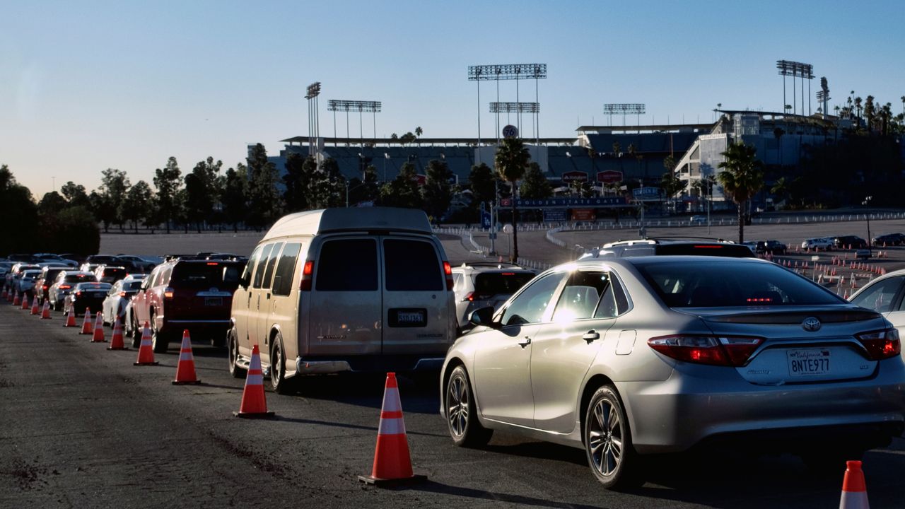 Los Angeles residents wait in line in their cars during the early morning to receive a COVID-19 vaccine at Dodger Stadium, in Los Angeles on Tuesday, Jan. 26, 2021. (AP Photo/Richard Vogel)