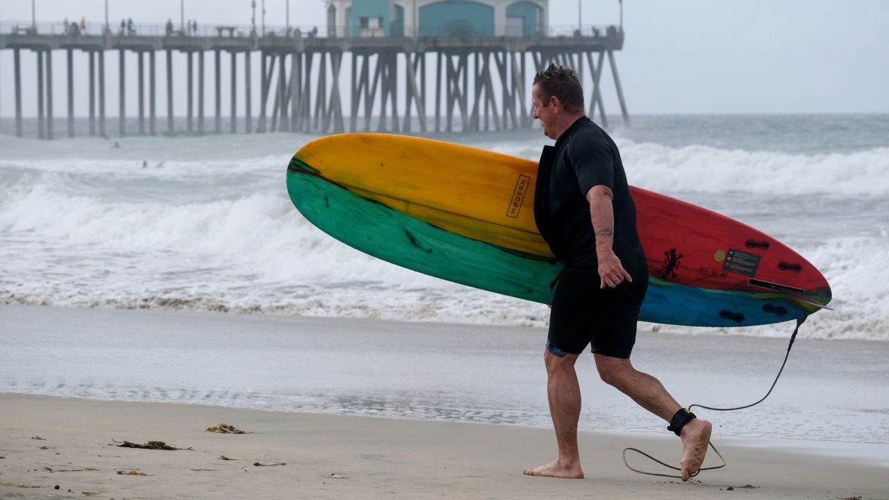 A surfer leaves the water in Huntington Beach, Calif., Monday, Oct. 11, 2021. (AP Photo/Ringo H.W. Chiu)