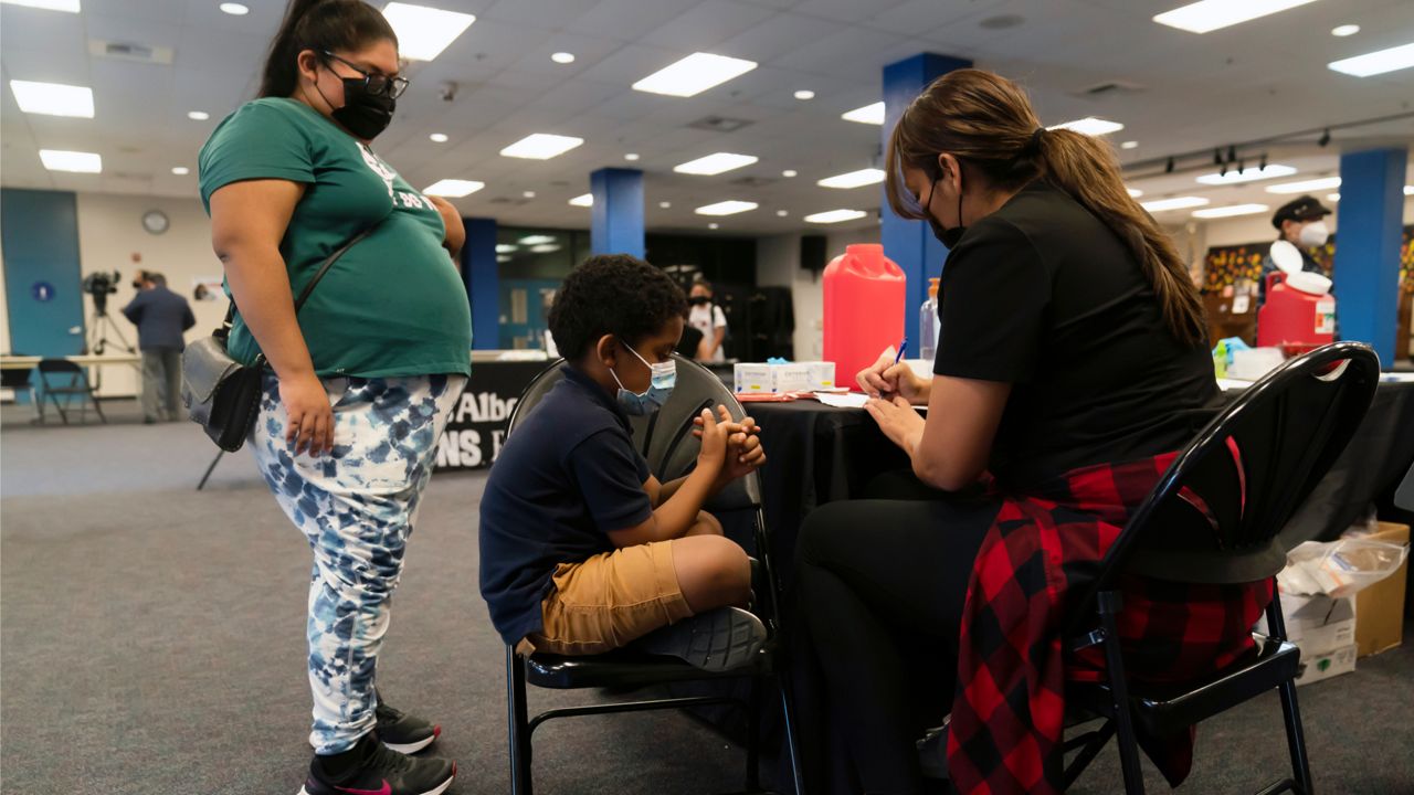 Five-year-old Amir Thompkins, center, waits to receive the Pfizer COVID-19 vaccine at a pediatric vaccine clinic for children ages 5 to 11 set up at Willard Intermediate School in Santa Ana, Calif., Tuesday, Nov. 9, 2021. (AP Photo/Jae C. Hong)