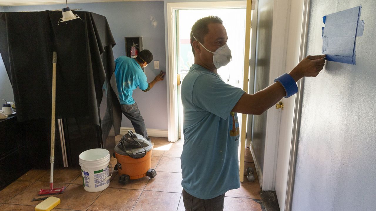 Volunteers wear face masks as they help renovate the Pasadena Community Job Center while it is closed to the public Thursday, May 7, 2020, in Pasadena, Calif. (AP Photo/Damian Dovarganes)