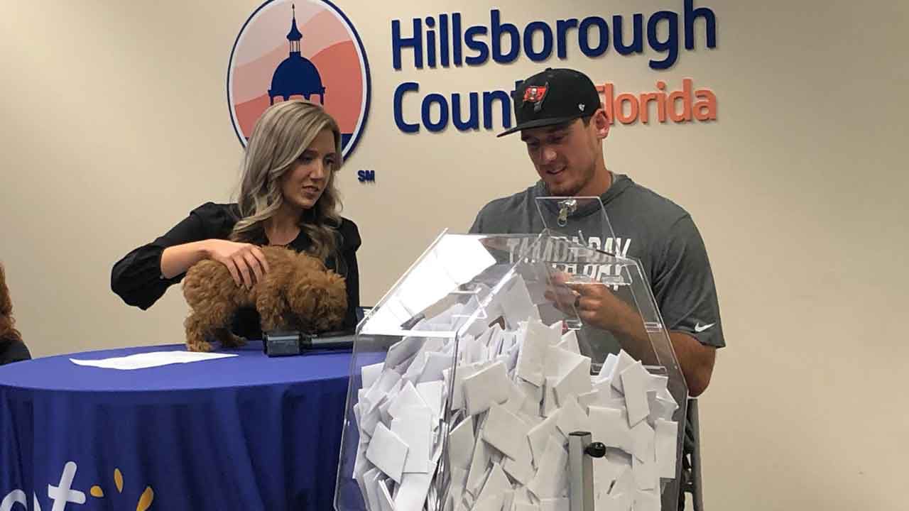 Tampa Bay Buccaneers punter Bradley Pinion draws names of applicants vying to adopt one of hundreds of puppies seized from a Tampa breeder during a special Hillsborough County adoption event, Thursday, Nov. 14, 2019. (Laurie Davison/Spectrum Bay News 9)