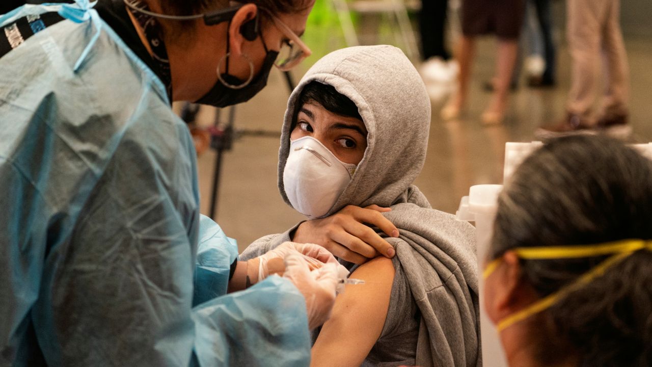 In this May 24, 2021, file photo, a student looks back at his mother as he is vaccinated at a school-based COVID-19 vaccination clinic for students 12 and older in San Pedro, Calif. (AP Photo/Damian Dovarganes, File)