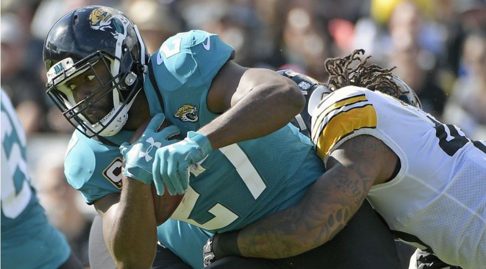 FILE - In this Nov. 18, 2018, file photo, Jacksonville Jaguars running back Leonard Fournette, left, runs for yardage as he is stopped by Pittsburgh Steelers outside linebacker Bud Dupree, right, during the first half of an NFL football game in Jacksonville, Fla. Jaguars coach Doug Marrone says Fournette was responding to racial slurs while yelling at a fan in Nashville, Tenn., last Thursday, Dec. 6, 2018. Fournette declined to address the accusation in the locker room Monday, Dec. 10, 2018, on the advice of his agent. (AP Photo/Phelan M. Ebenhack, File)