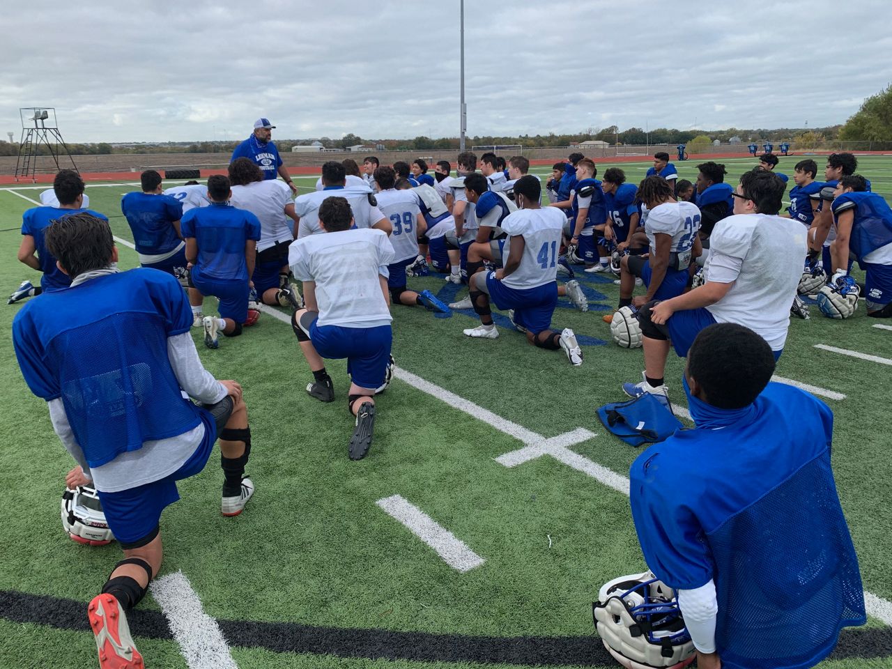 The Lehman High School football team kneel together on the field. (Spectrum News)