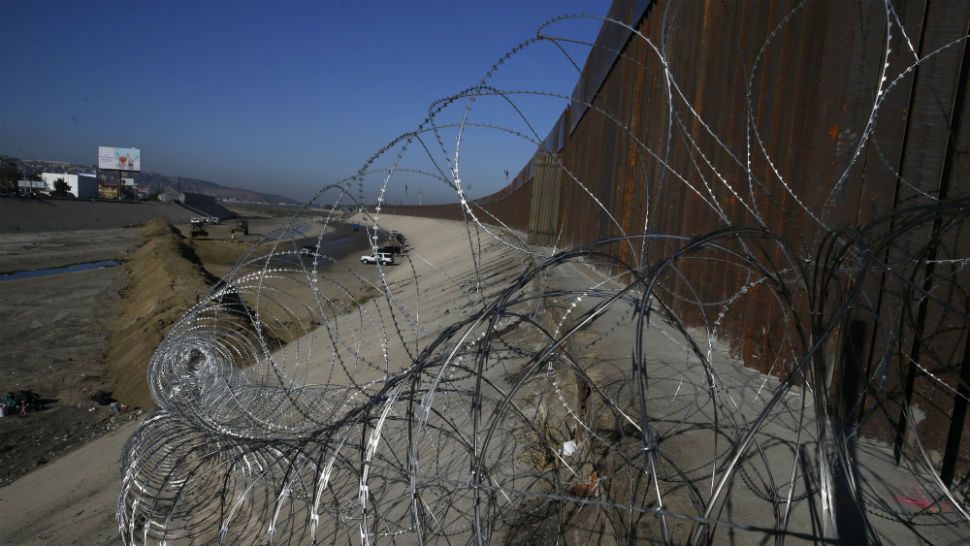 Barbed wire hangs on the U.S. border fence in San Ysidro, seen from Tijuana, Mexico, Sunday, Nov. 18, 2018. While many in Tijuana are sympathetic to the plight of Central American migrants and trying to assist, some locals have shouted insults, hurled rocks and even thrown punches at the migrants. (AP Photo/Marco Ugarte)