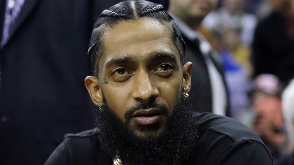 FILE - This March 29, 2018 file photo shows rapper Nipsey Hussle at an NBA basketball game between the Golden State Warriors and the Milwaukee Bucks in Oakland, Calif. Hussle, who was shot and killed outside of his clothing store in Los Angeles on March 31, 2019, received three Grammy nominations on Wednesday, Nov. 20. His song “Racks In the Midldle is up for best rap performance and best rap song, while “Higher,” a collaboration with DJ Khaled and John Legend that one of the last songs Hussle recorded, is nominated for best rap/sung performance.. (AP Photo/Marcio Jose Sanchez, File)