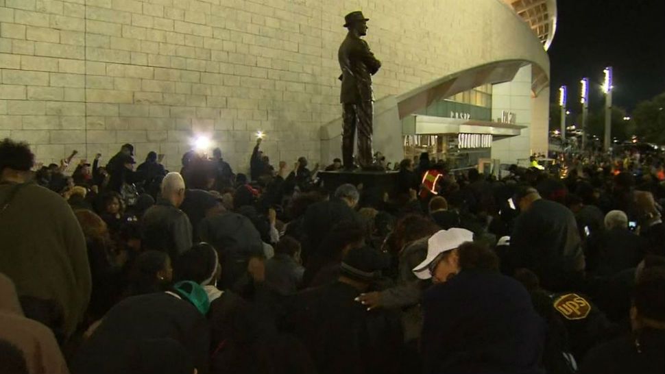 Protesters kneel in front of Tom Landry's statue at AT&T stadium. 