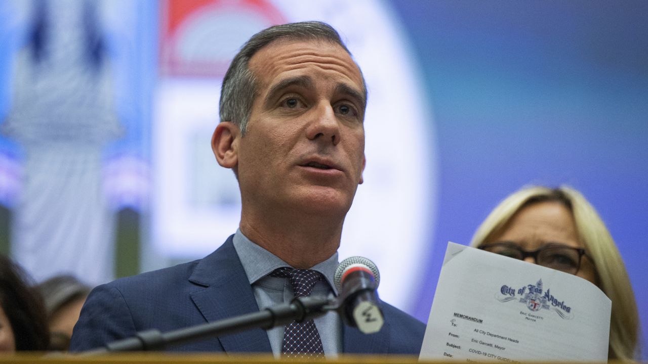 Los Angeles Mayor Eric Garcetti shows a Memorandum with COVID-19 city departments guidelines, as he takes questions at a news conference in Los Angeles, Thursday, March 12, 2020. (AP Photo/Damian Dovarganes)