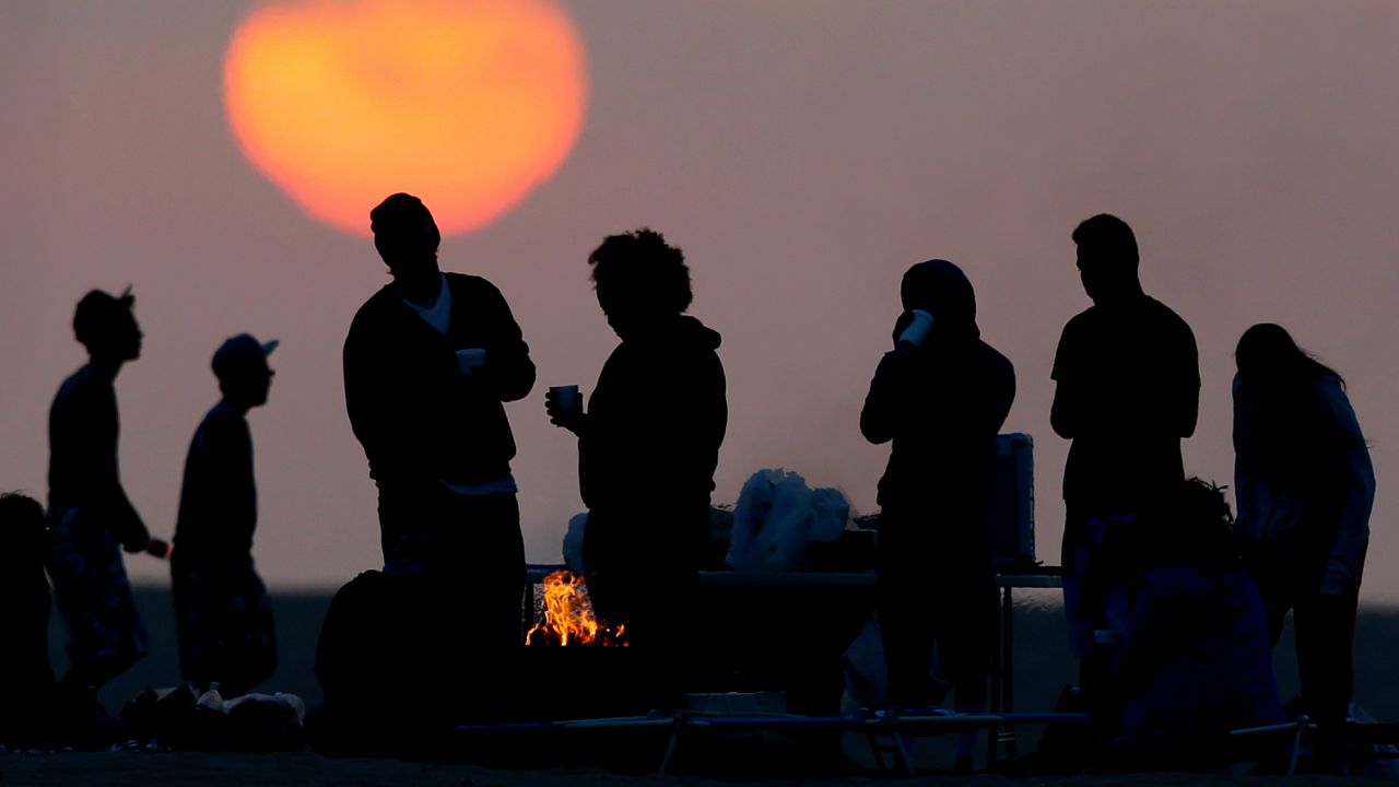 Beach goers stand around a fire pit on April 28, 2013 in Huntington Beach, Calif. (AP Photo/Chris Carlson)