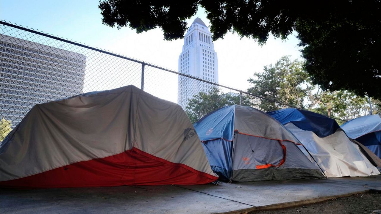 This July 1, 2019 photo shows Los Angeles City Hall behind a homeless tent encampment along a street in downtown Los Angeles. (AP Photo/Richard Vogel)