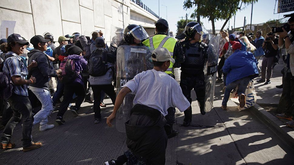 Migrants break past a line of police as they run toward the Chaparral border crossing in Tijuana, Mexico, Sunday, Nov. 25, 2018, near the San Ysidro entry point into the U.S. (AP Photo/Ramon Espinosa)