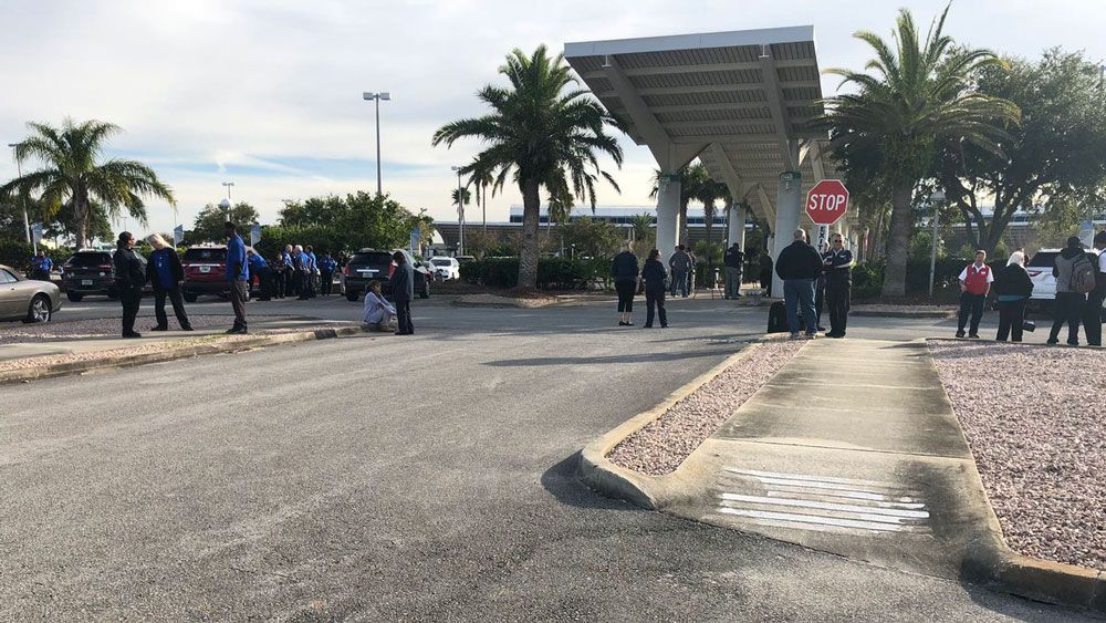 Evacuated patrons and airport staff  stand outside Daytona Beach International Airport while law enforcement clears a suspicious bag. It turned out the bag included a toothbrush. (Brittany Jones, Spectrum News)