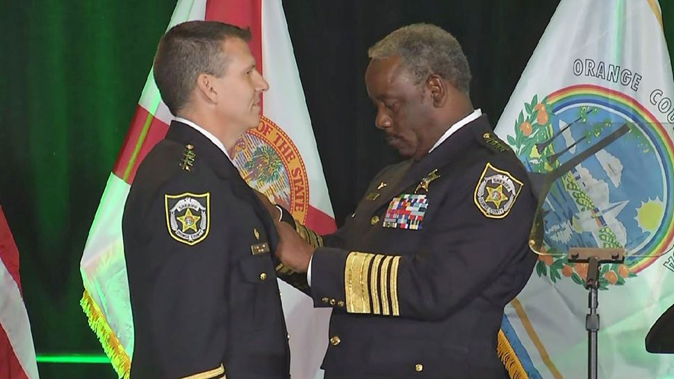 Former Orlando Police Chief John Mina is pinned by former Orange County Sheriff Jerry Demings during a swearing in ceremony. (Spectrum News 13)