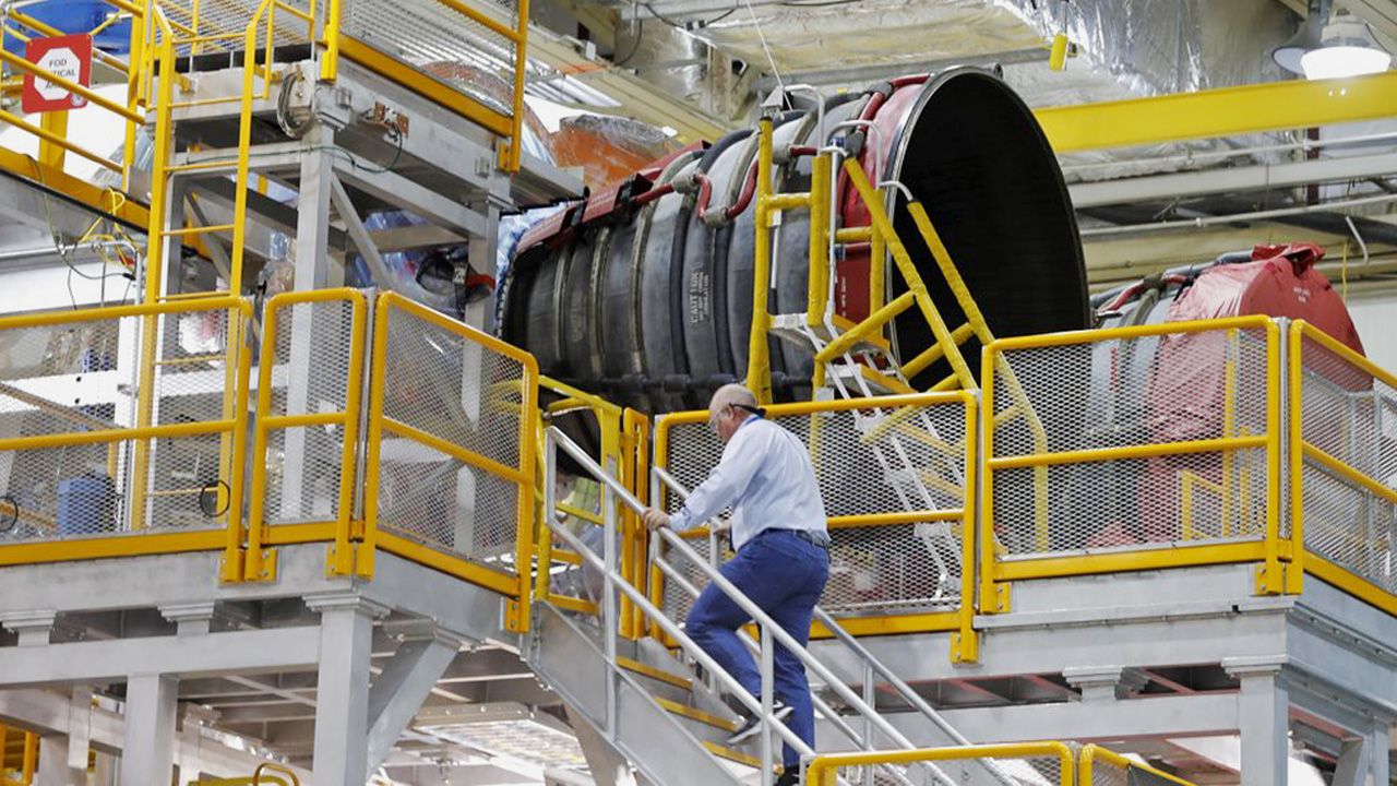 An employee walks up to two of the four rocket engines of NASA's Space Launch System (SLS) as the Artemis 1 rocket core stage is assembled at the NASA Michoud Assembly Center in New Orleans, Monday, Dec. 9, 2019. (AP Photo/Gerald Herbert)