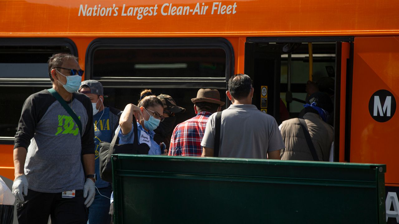 Los Angeles Metro commuters board a bus in Los Angeles on Thursday, May 14, 2020. (AP Photo/Damian Dovarganes)