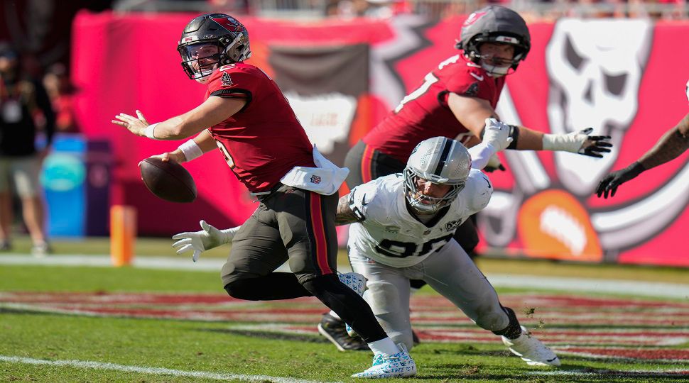 Tampa Bay Buccaneers quarterback Baker Mayfield (6) runbs away from Las Vegas Raiders defensive end Maxx Crosby (98) during the first half of an NFL football game, Sunday, Dec. 8, 2024, in Tampa, Fla. (AP Photo/Chris O'Meara)