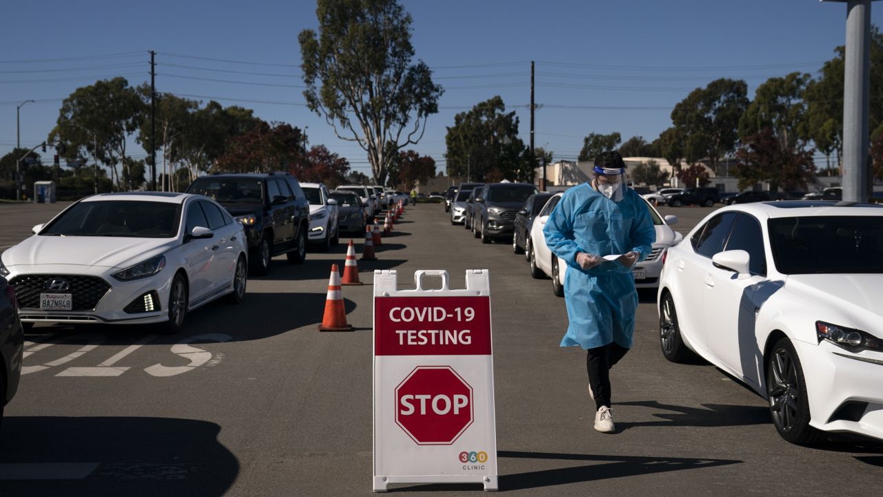 Student nurse Ryan Eachus collects forms as cars line up for COVID-19 testing at a testing site set up the OC Fairgrounds in Costa Mesa, Calif. on Nov. 16, 2020. (AP Photo/Jae C. Hong)