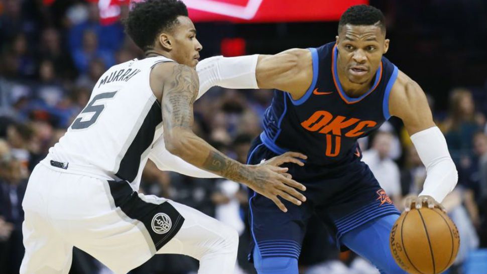 Oklahoma City Thunder guard Russell Westbrook (0) drives around San Antonio Spurs guard Dejounte Murray (5) during the first quarter of an NBA basketball game in Oklahoma City, Sunday, Dec. 3, 2017. (AP Photo/Sue Ogrocki)