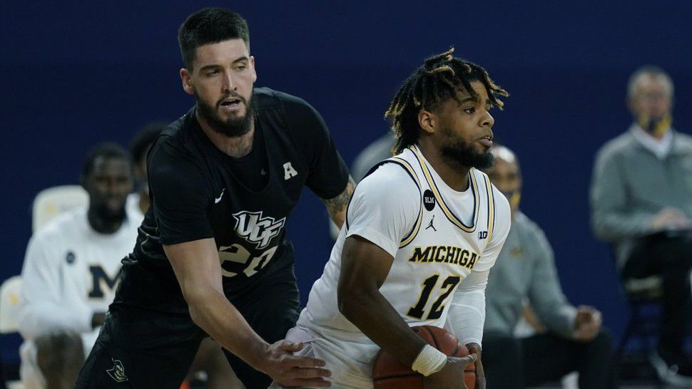 UCF forward Sean Mobley (20) reaches in against Michigan guard Mike Smith (12) during the second half of an NCAA college basketball game, Sunday, Dec. 6, 2020, in Ann Arbor, Mich. (AP Photo/Carlos Osorio)