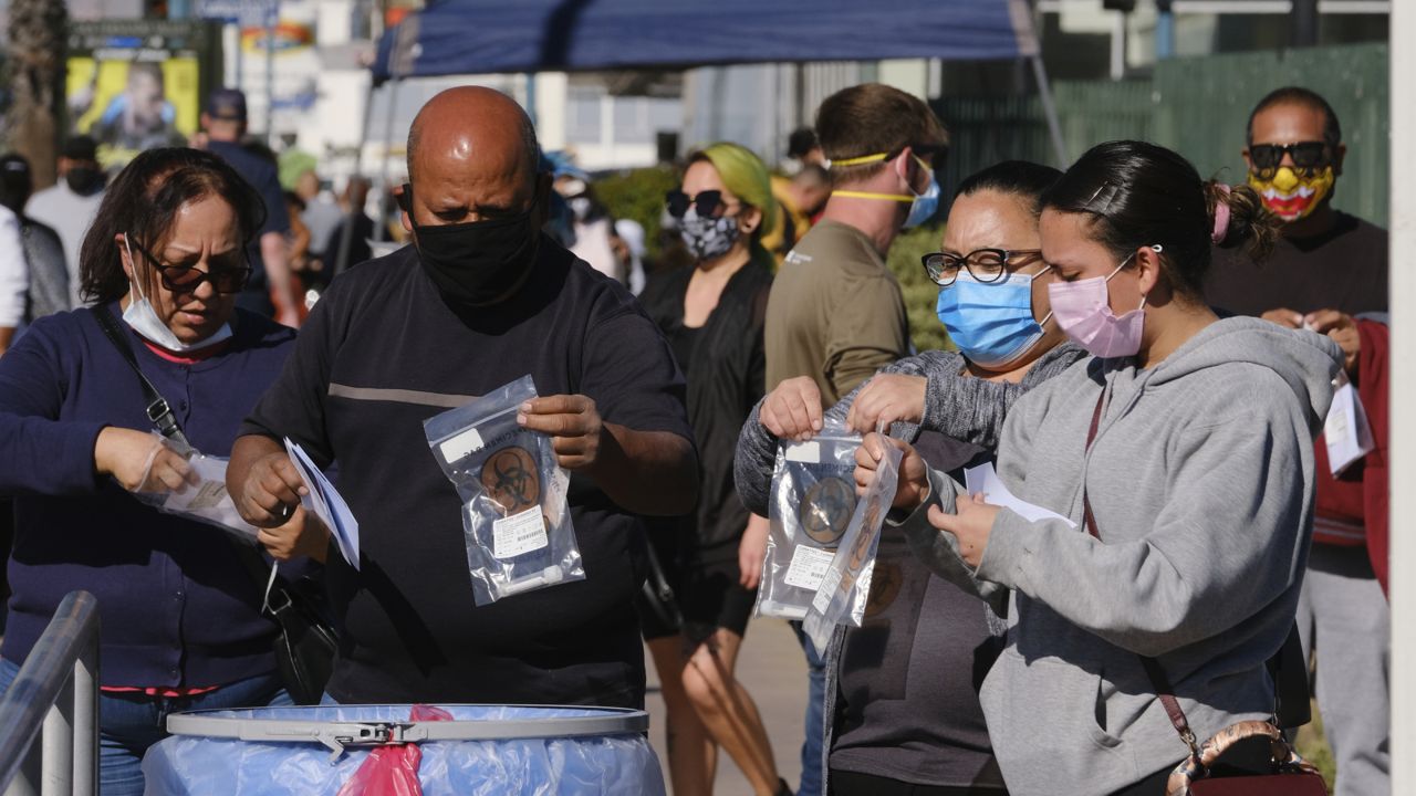 People drop their test kits into an intake receptacle at a Covid-19 testing site in the North Hollywood section of Los Angeles on Saturday, Dec. 5, 2020. (AP/Richard Vogel)