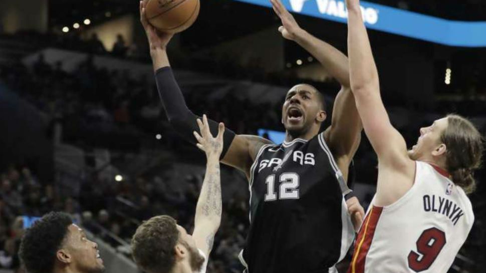 San Antonio Spurs forward LaMarcus Aldridge (12) shoots over Miami Heat defenders Kelly Olynyk (9) and Tyler Johnson (8) during the second half of an NBA basketball game, Wednesday, Dec. 6, 2017, in San Antonio. San Antonio won 117-105. (AP Photo/Eric Gay)