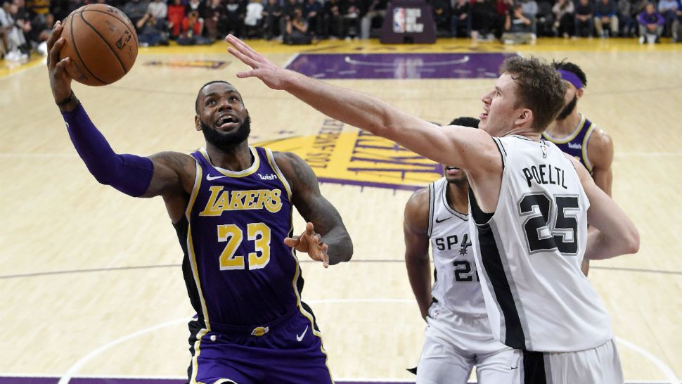 Los Angeles Lakers forward LeBron James, left, shoots as San Antonio Spurs center Jakob Poeltl, of Austria, defends during the second half of an NBA basketball game, Wednesday, Dec. 5, 2018, in Los Angeles. The Lakers won 121-113. (AP Photo/Mark J. Terrill)