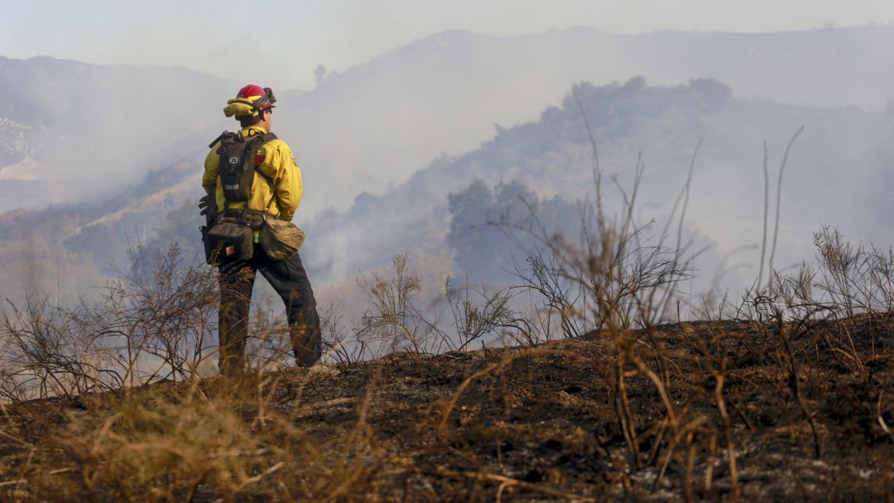 A firefighter watches while the Bond Fire burning in Silverado, Calif., on Thursday, Dec. 3, 2020. (AP Photo/Ringo H.W. Chiu)