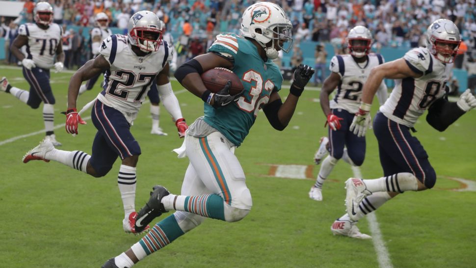 FILE - In this Dec. 9, 2018, file photo, Miami Dolphins running back Kenyan Drake (32) runs for a touchdown during the second half of an NFL football game against the New England Patriots, in Miami Gardens, Fla. The Miami Dolphins are trying to move past the euphoria of their last-play victory over division rival New England and keep their postseason momentum alive at Minnesota. (AP Photo/Lynne Sladky, File)