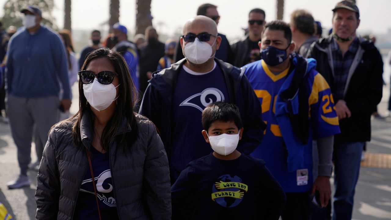 Fans wears masks amid the COVID-19 pandemic as they enter SoFi Stadium before an NFL football game between the Los Angeles Rams and the Jacksonville Jaguars Sunday, Dec. 5, 2021, in Inglewood, Calif. (AP Photo/Jae C. Hong)