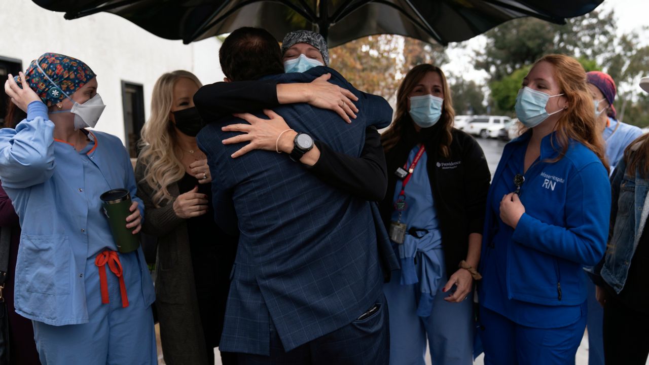 Registered nurse Lisa Lampkin, center, facing camera, hugs her former COVID-19 patient, Brian Patnoe, at Providence Mission Hospital in Mission Viejo, Calif., Thursday, Dec. 9, 2021, as former coronavirus patients and their caregivers gather to celebrate the hospital's 50th anniversary. (AP Photo/Jae C. Hong)