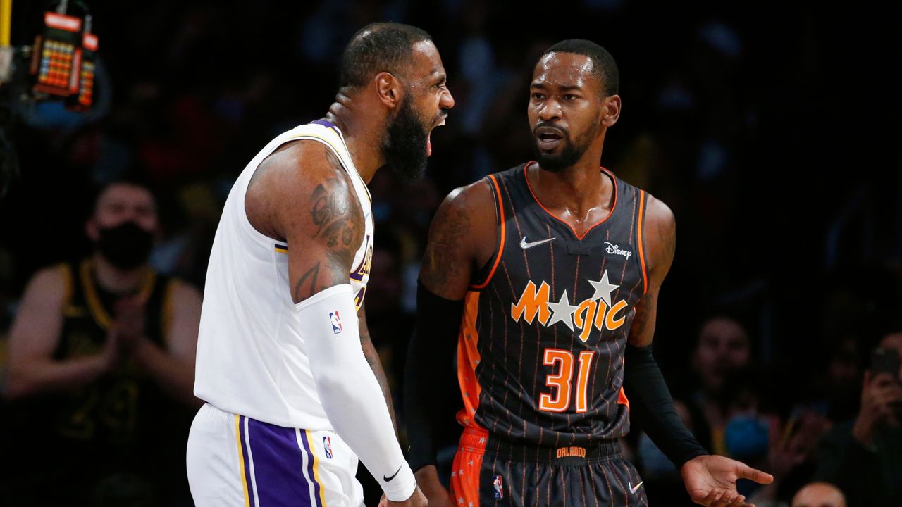 Los Angeles Lakers forward LeBron James, left, reacts next to Orlando Magic guard Terrence Ross after making a slam dunk during the first half of an NBA basketball game in Los Angeles, Sunday, Dec. 12, 2021. (AP Photo/Ringo H.W. Chiu)