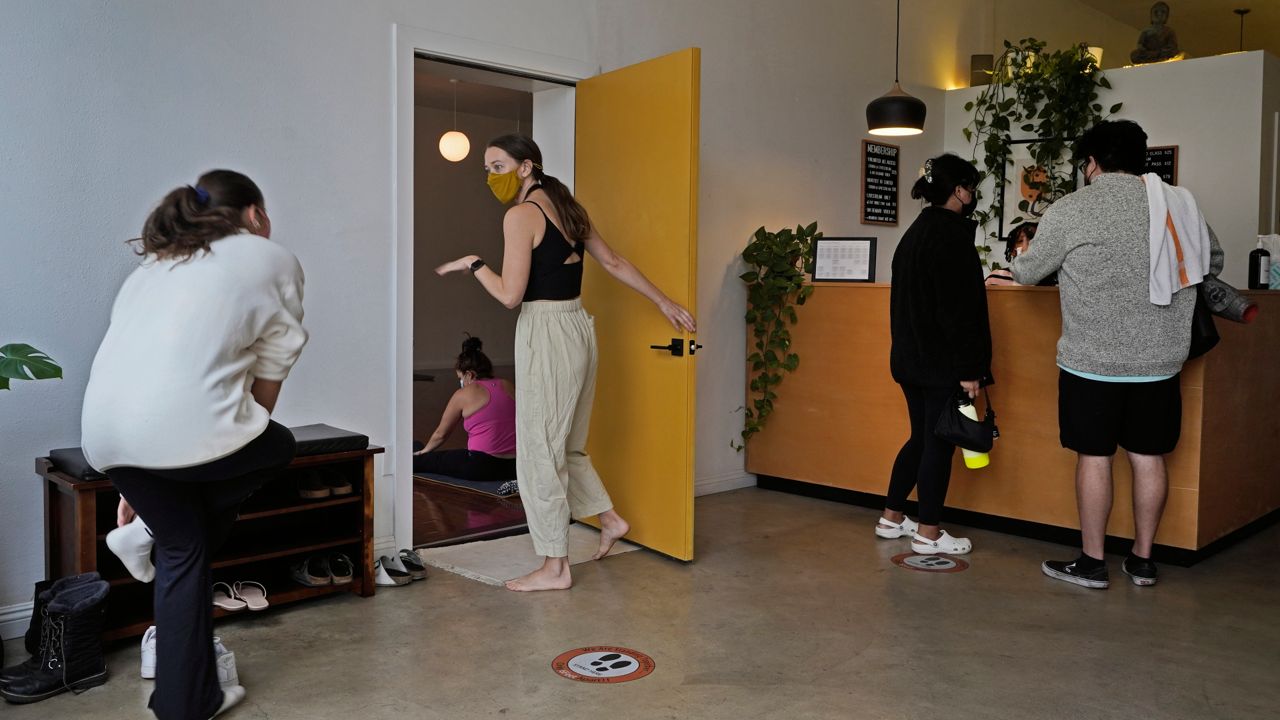 Yoga instructor Lydia Stone, center, welcomes patrons arriving for a morning yoga class at the Highland Park Yoga studio in Los Angeles, Nov. 6, 2021. (AP Photo/Damian Dovarganes)