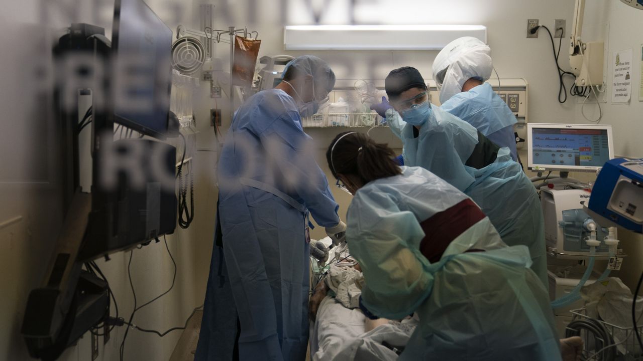 EMT Giselle Dorgalli, second from right, looks at a monitor while performing chest compression on a patient who tested positive for coronavirus in the emergency room at Providence Holy Cross Medical Center in the Mission Hills section of Los Angeles on Nov. 19, 2020. (AP Photo/Jae C. Hong)