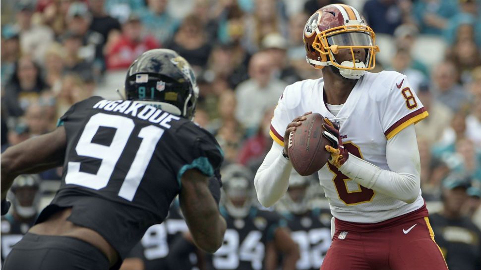 Washington Redskins quarterback Josh Johnson (8) looks for a receiver as he is pressured by Jacksonville Jaguars defensive end Yannick Ngakoue (91) during the first half of an NFL football game, Sunday, Dec. 16, 2018, in Jacksonville, Fla. (AP Photo/Phelan M. Ebenhack)