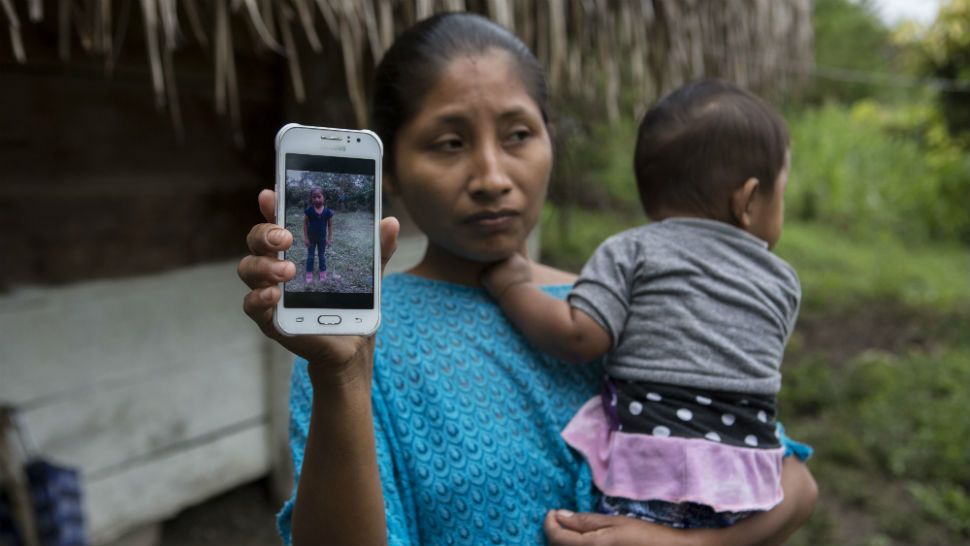 Claudia Maquin, 27, shows a photo of her daughter, Jakelin Amei Rosmery Caal Maquin in Raxruha, Guatemala, on Saturday, Dec. 15, 2018. The 7-year-old girl died in a Texas hospital, two days after being taken into custody by border patrol agents in a remote stretch of New Mexico desert. (AP Photo/Oliver de Ros)